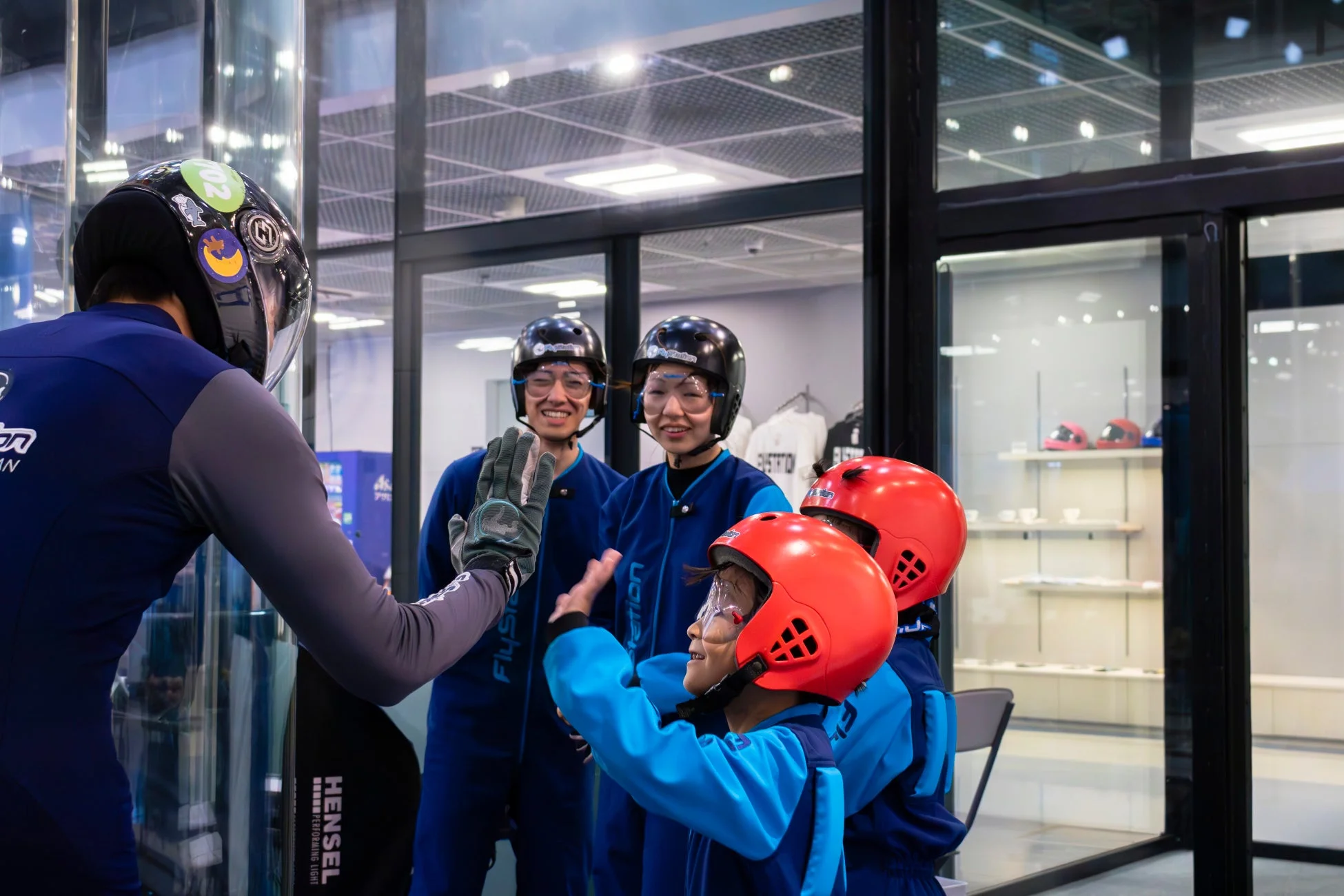 フライトスーツとヘルメットを着用した人々がインストラクターと交流しています