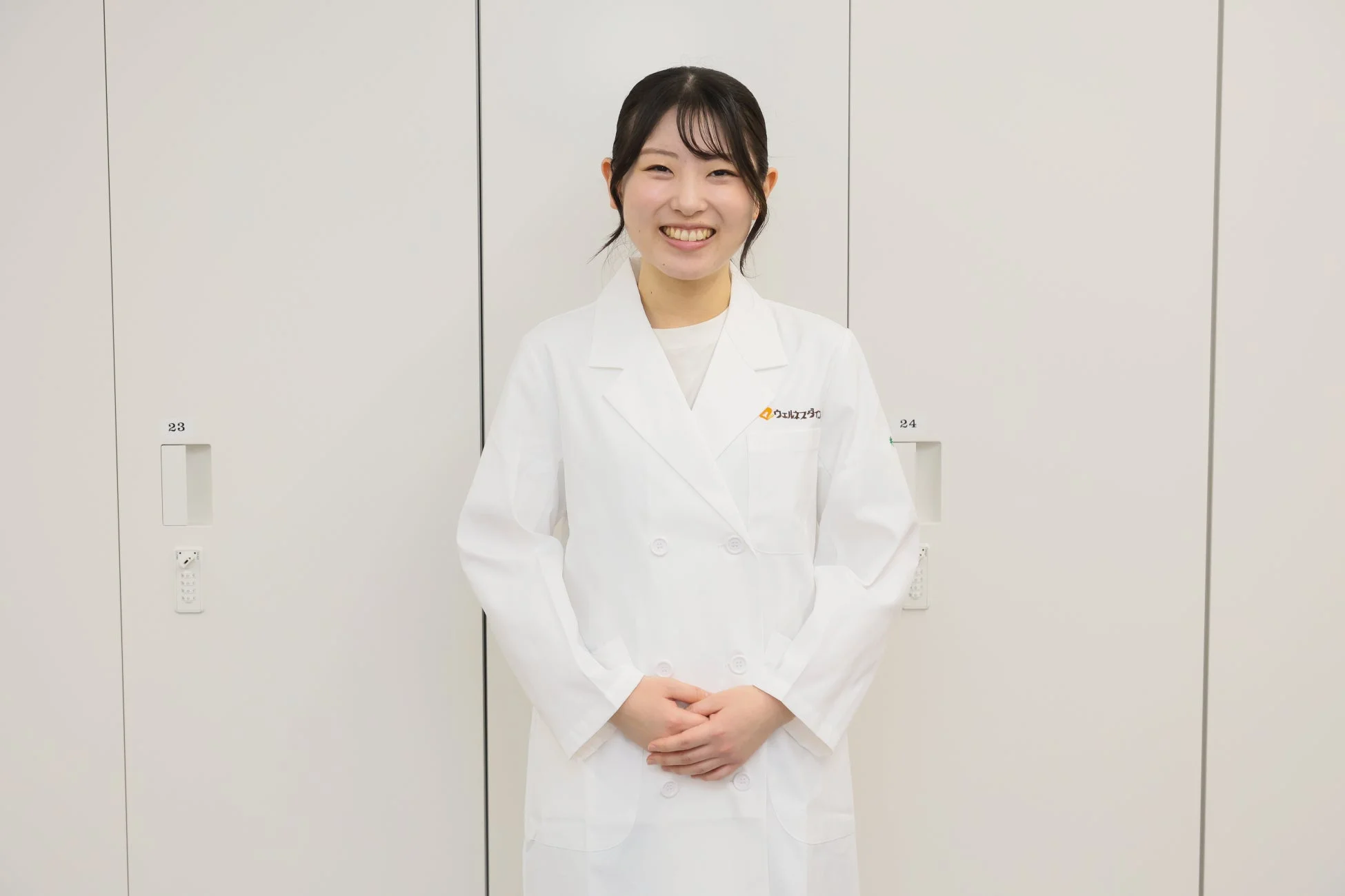 白衣を着て笑顔で立つ管理栄養士の女性