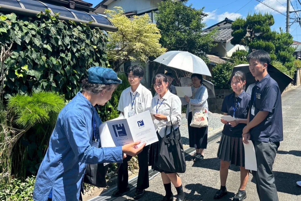 学生がガイドブックを見ながら説明を受ける様子