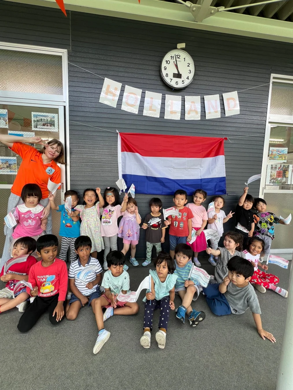 子供たちと先生がオランダ国旗の前でポーズ