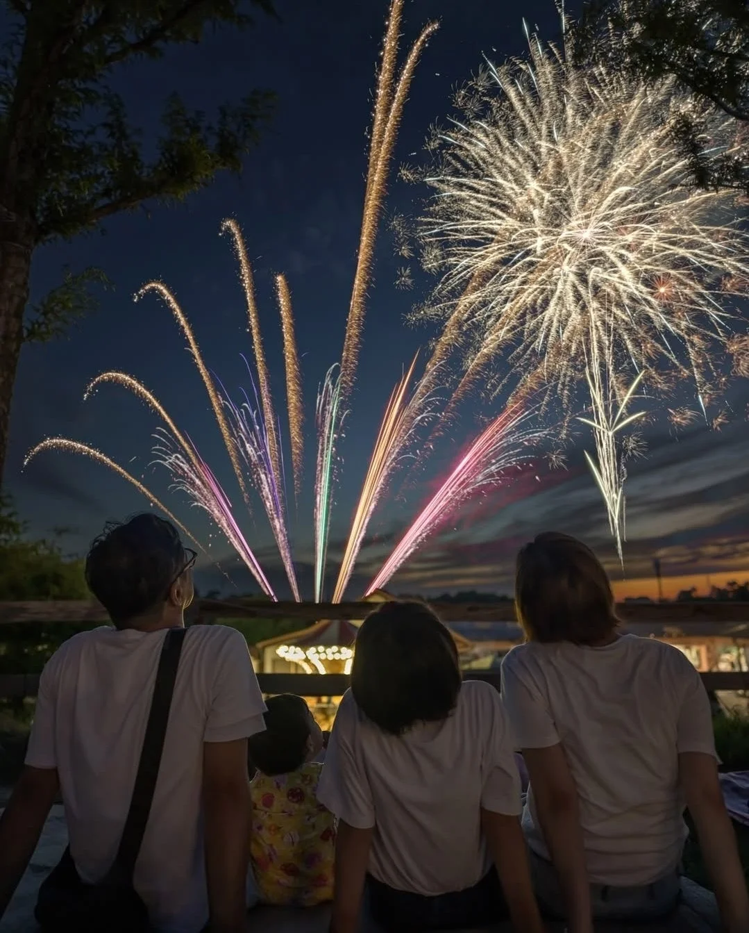 夜空に打ち上がる花火を鑑賞する家族