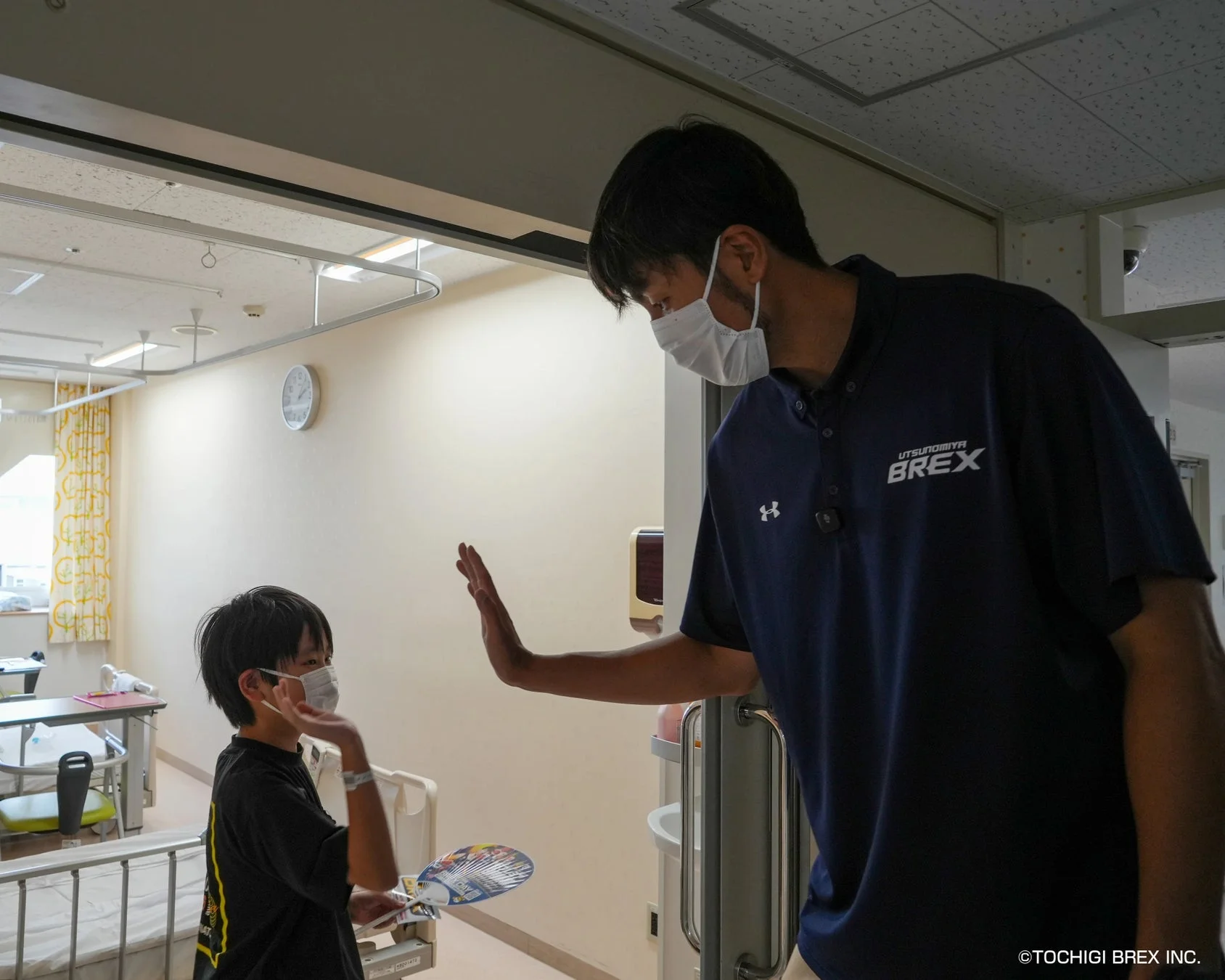 病室で子どもとハイタッチを交わす竹内選手