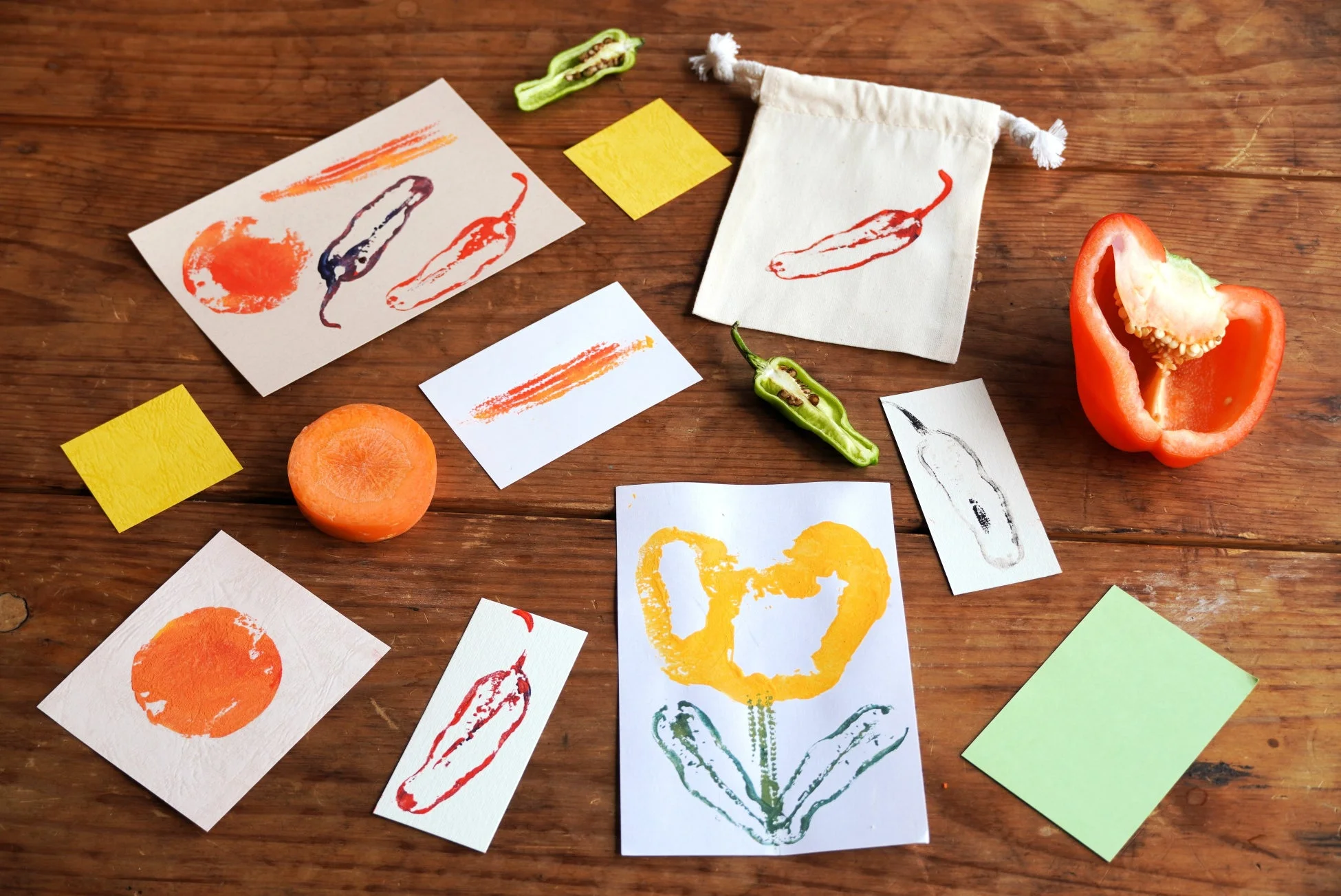 木製のテーブルの上に、野菜を使ったスタンプアート作品と材料が並べられています