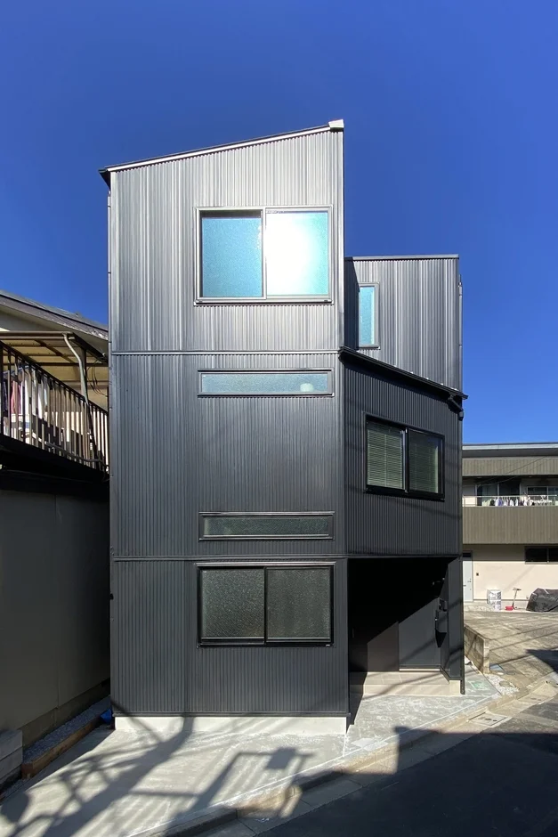 ガルバリウム鋼板の外壁を持つモダンな3階建ての狭小住宅