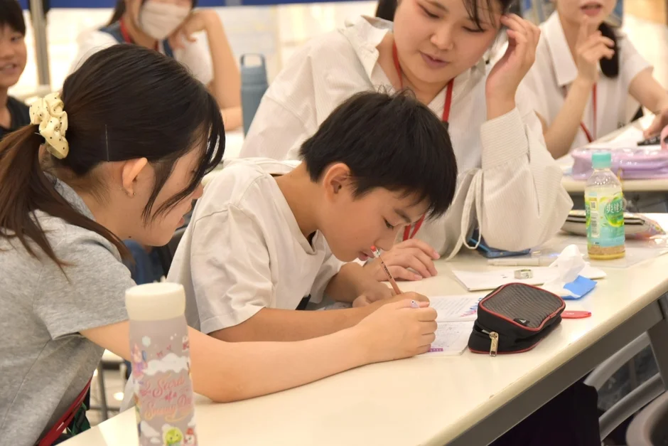 数人の子供や若者が机に向かい、集中して勉強や学習に取り組んでいる様子