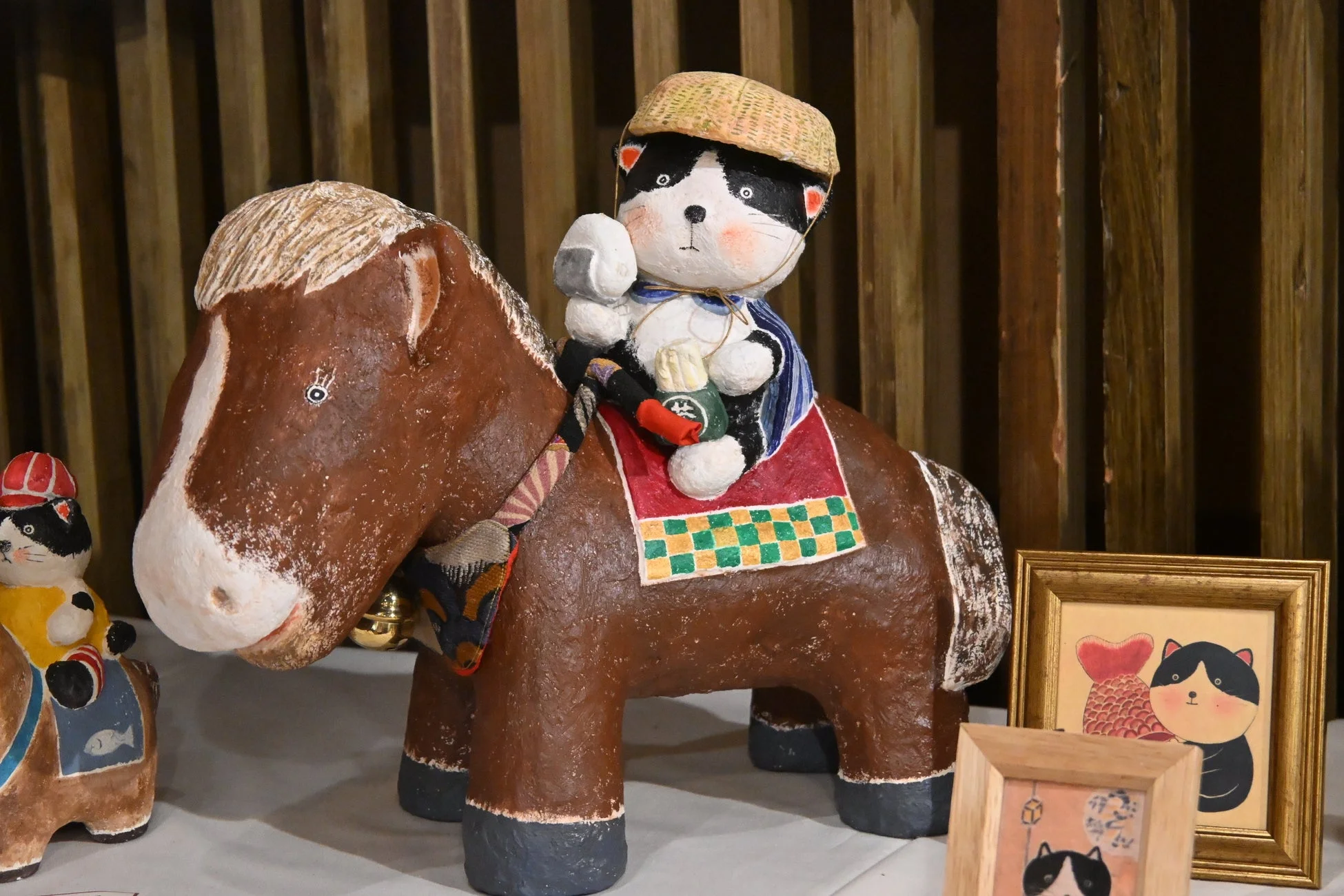 麦わら帽子をかぶった猫が馬に乗る張り子の置物