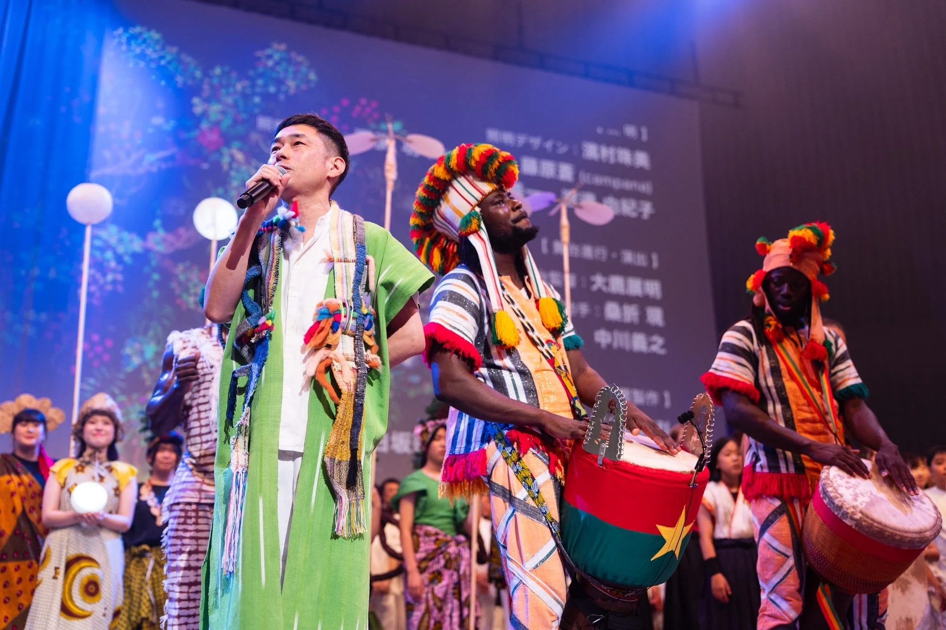 アフリカの民族衣装を着たパフォーマーたちがドラムを演奏するライブパフォーマンス
