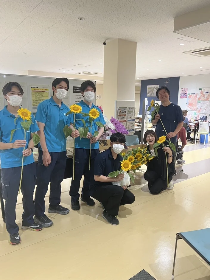 ひまわりを持つ人々の集合写真