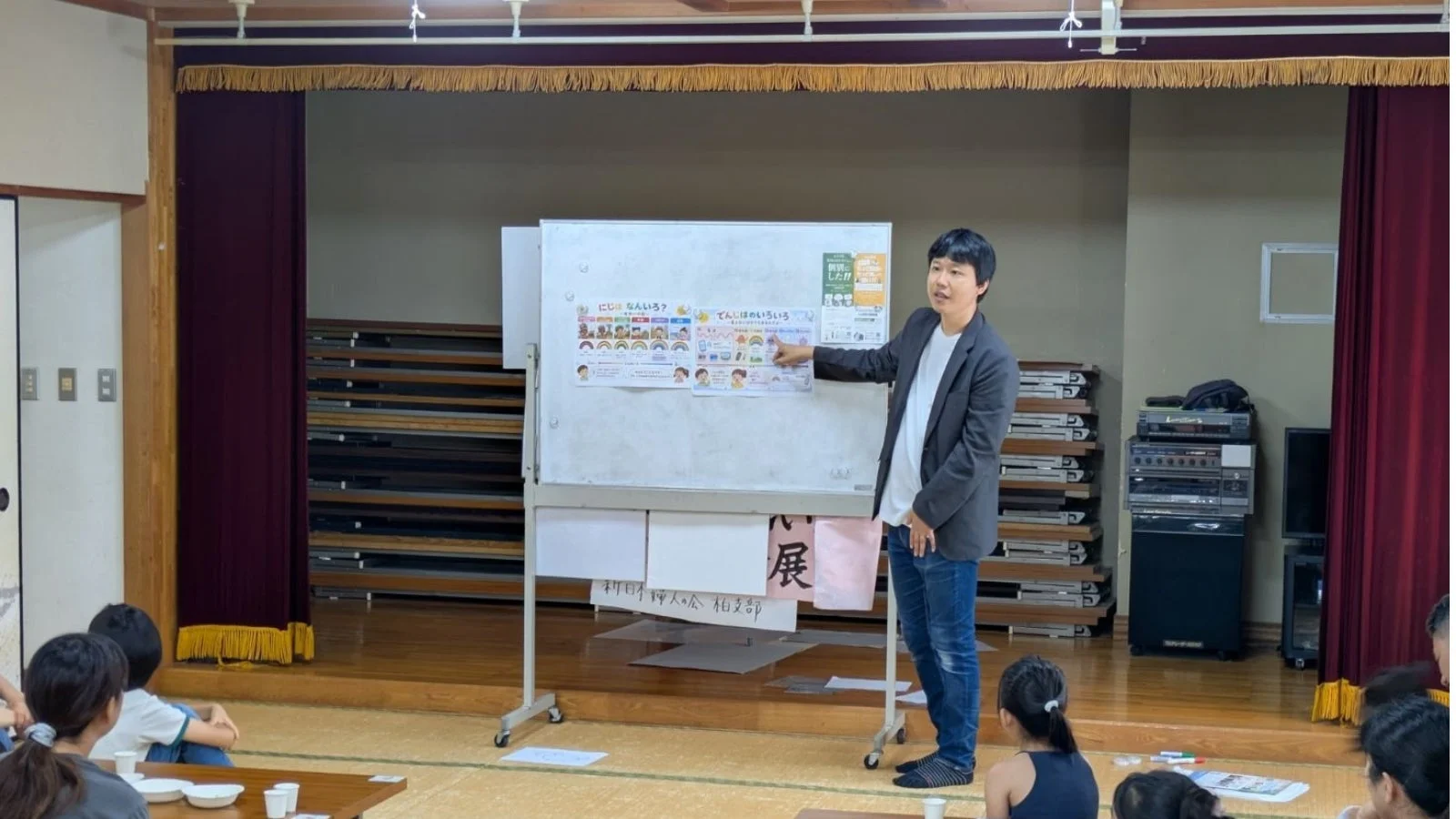 和室で男性が子供たちにホワイトボードを使って説明している様子