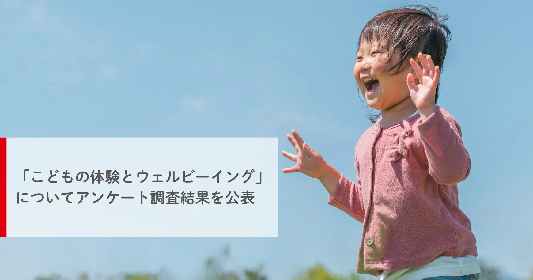 青空の下、満面の笑みで両手を広げる幼い子供