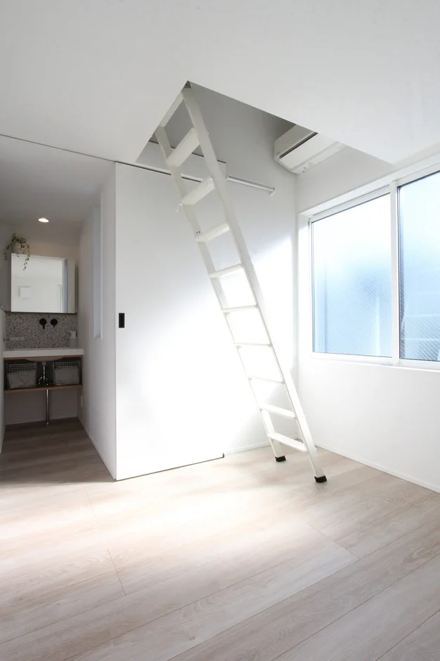 白い壁と明るい木目調の床が特徴のモダンなロフト付きの部屋