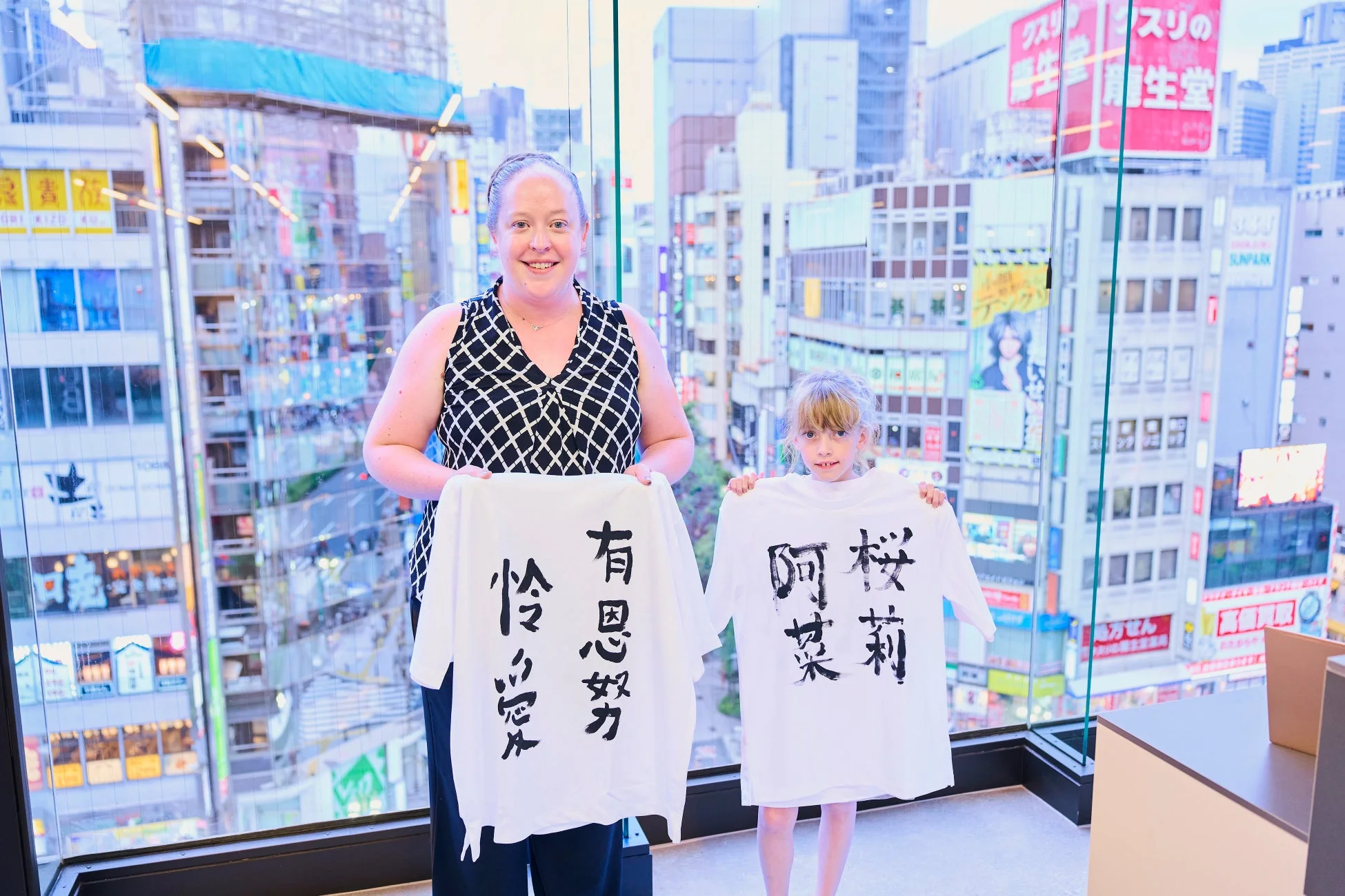 母親と娘が書道作品Tシャツを持つ