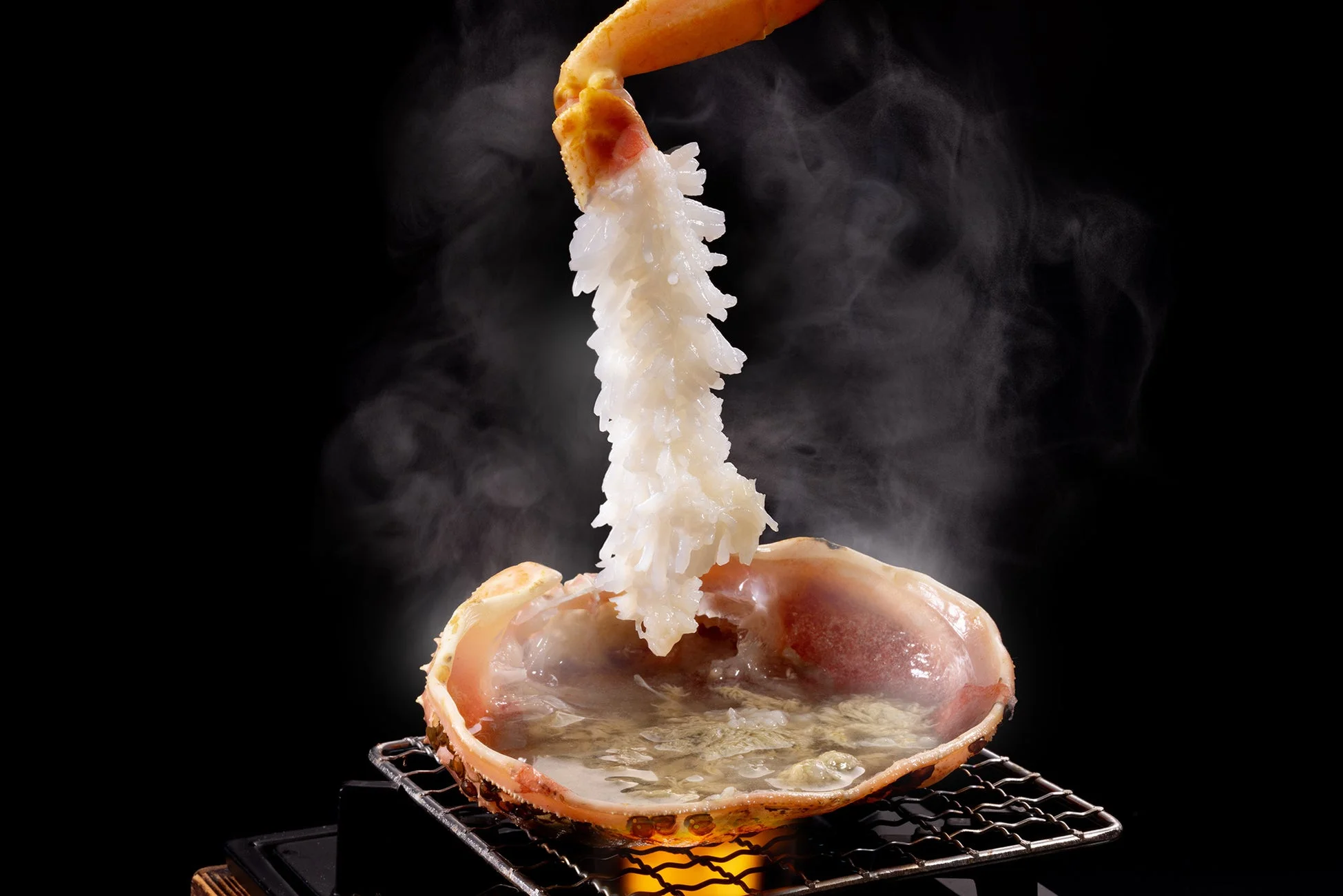 湯気を立てるカニの甲羅の上で提供されるカニ料理