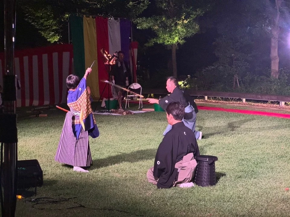 夜の野外ステージで剣舞のような伝統芸能を披露する人々