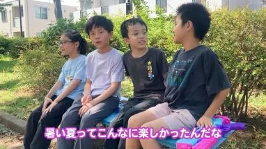 屋外でベンチに座って楽しそうに会話する4人の子どもたち