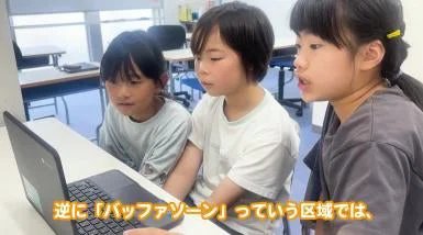 教室でノートパソコンの画面をのぞき込む3人の子どもたち
