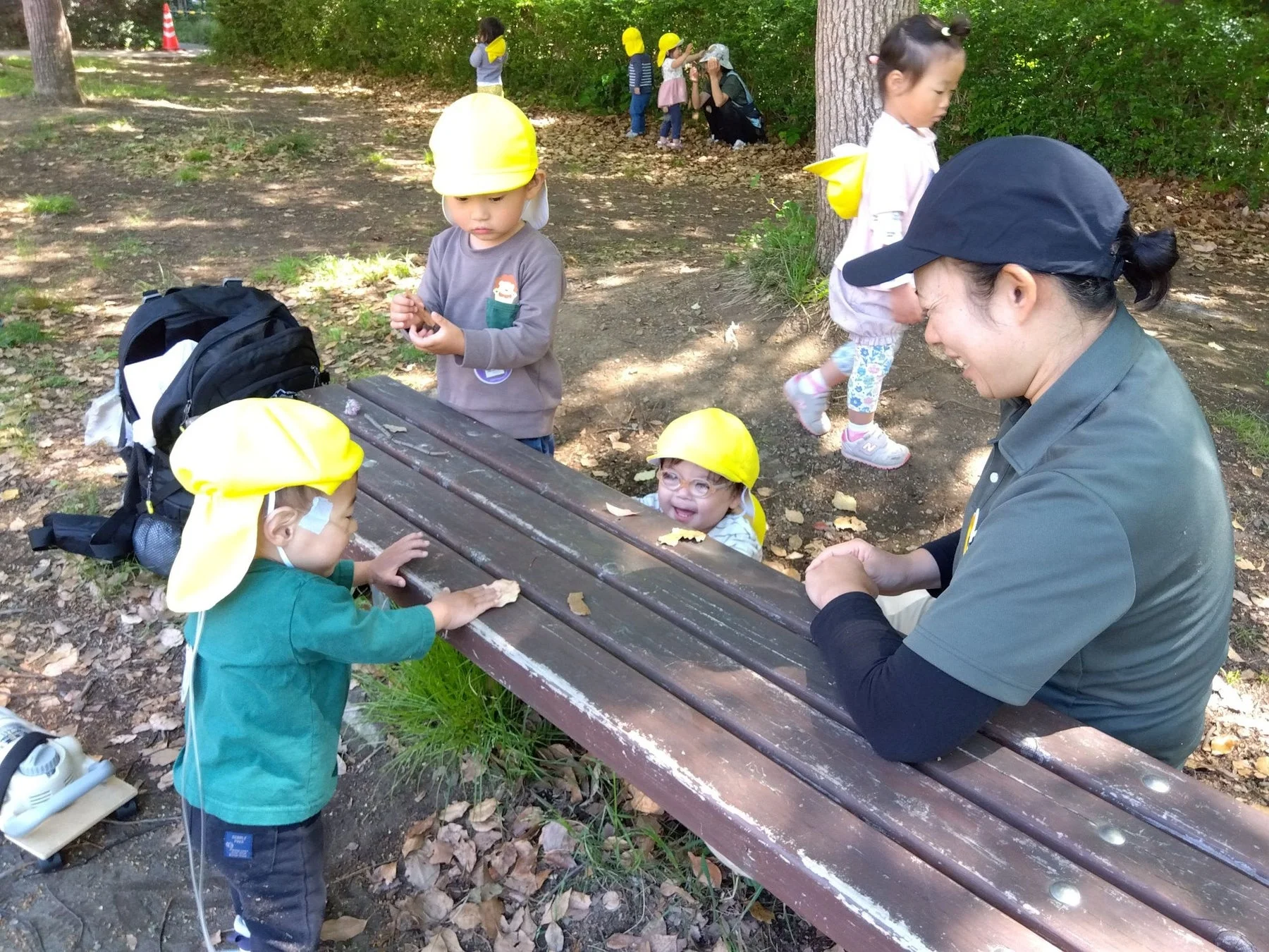 公園で保育園児たちが先生と一緒に遊んでいる様子