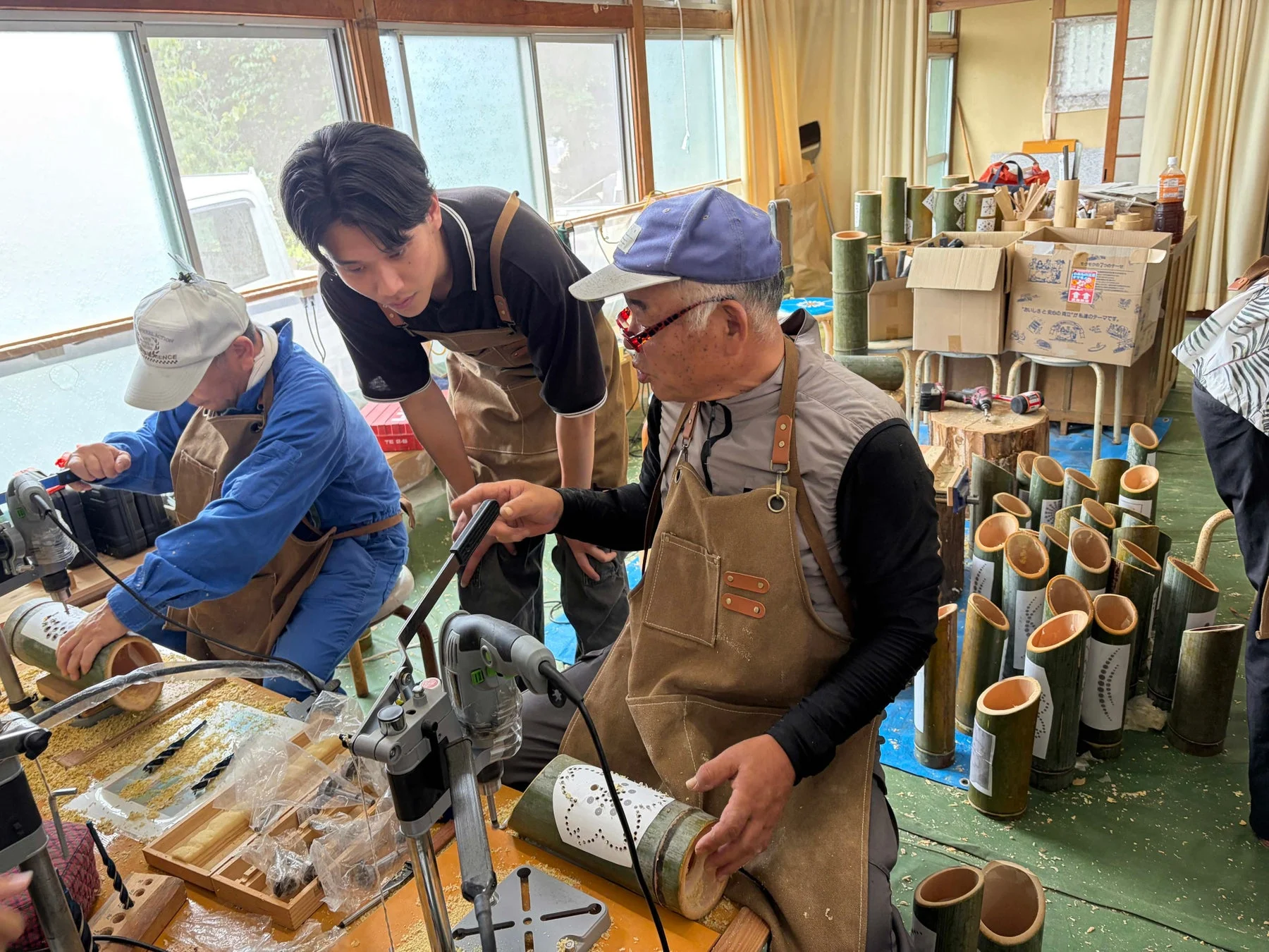 工房で複数の男性が竹を使って作品を制作している様子