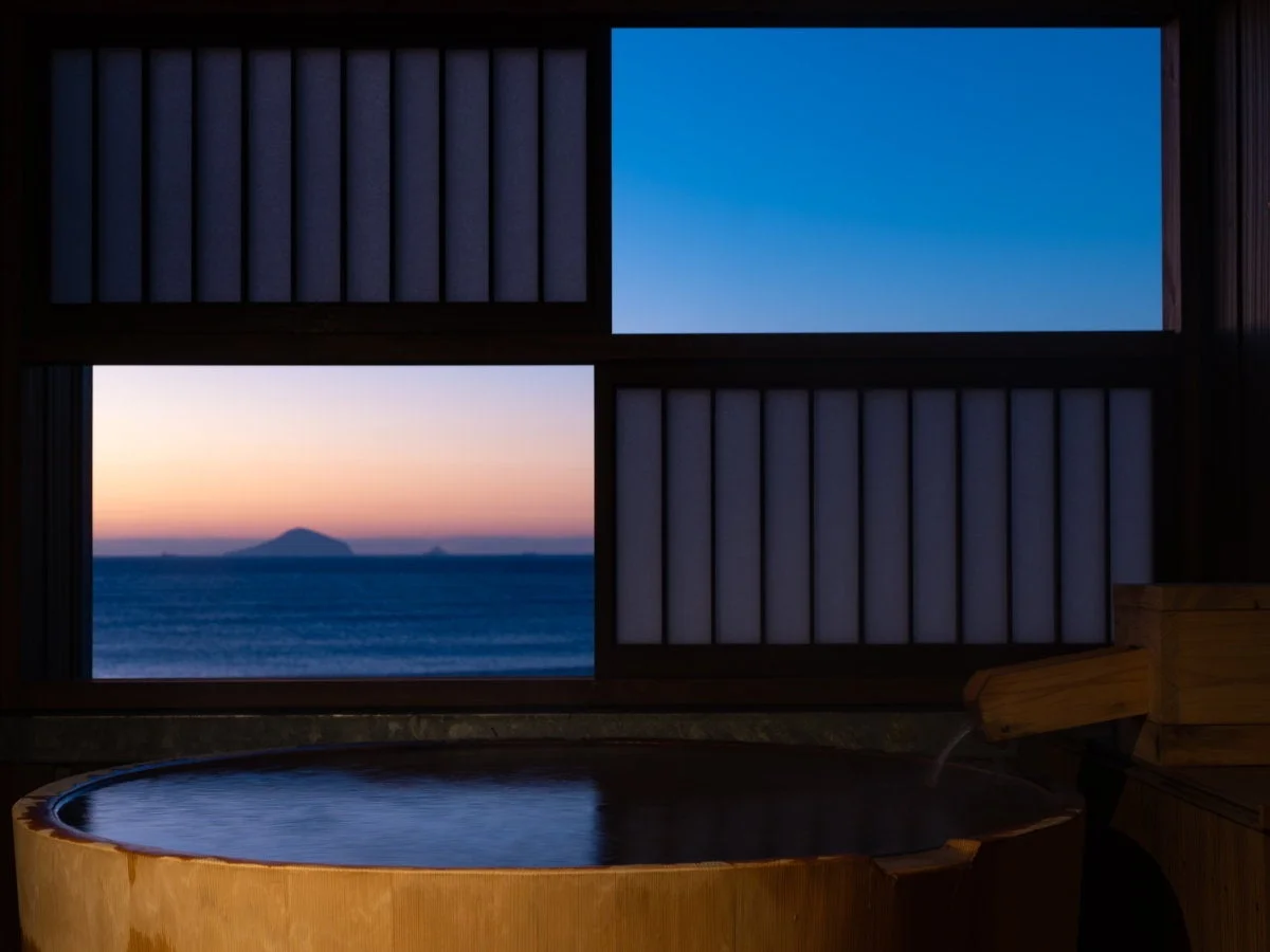 窓から夕焼けに染まる海を望む露天風呂