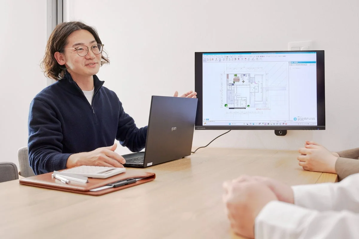 会議室で間取り図を説明する男性
